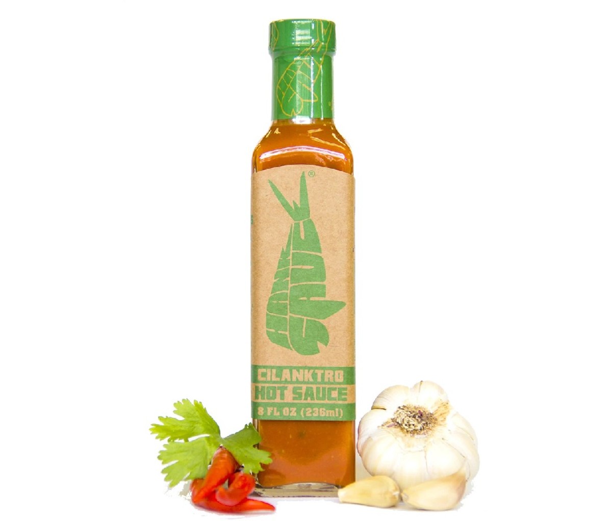 Bottle of Hank Sauce Cilanktro sauce beside a garlic bulb and hot red pepper garnish