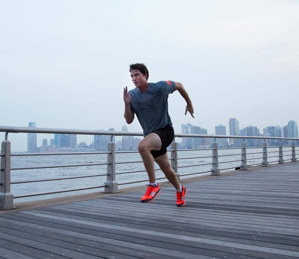 Best HIIT Workouts: Man doing sprints on walkway with cityscape background.