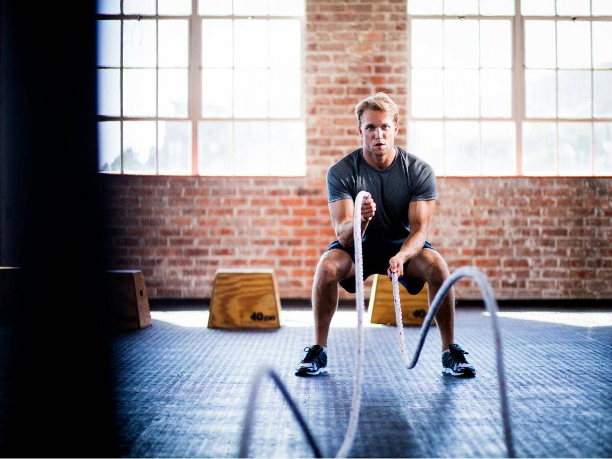 Best HIIT Workouts: Man in gym using battle ropes