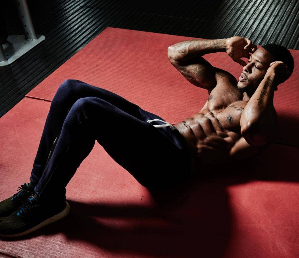 Best HIIT Workouts: Shirtless black man in dark blue sweats doing crunches