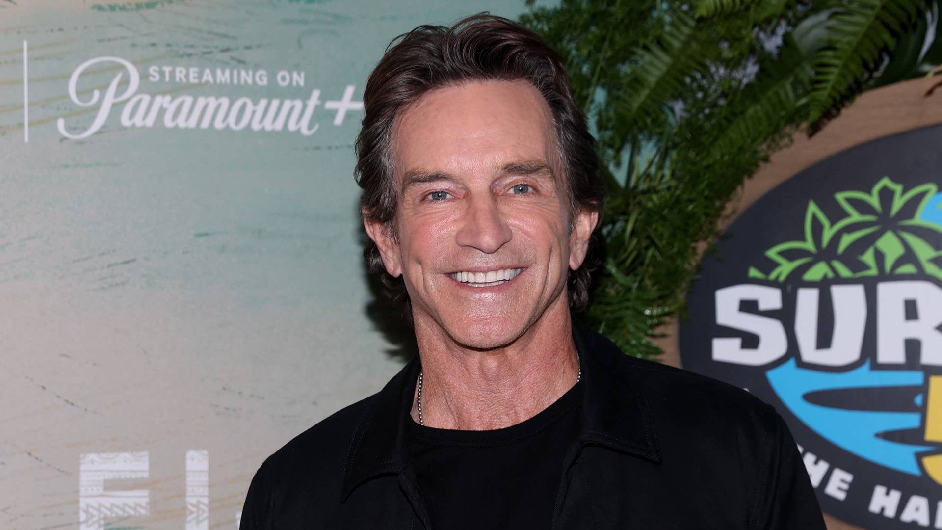 Jeff Probst smiling confidently while posing on the red carpet.
