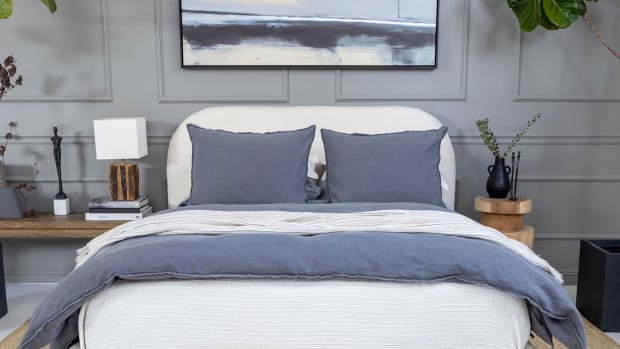 Denim blue duvet cover on a white upholstered bed in a masculine bedroom.