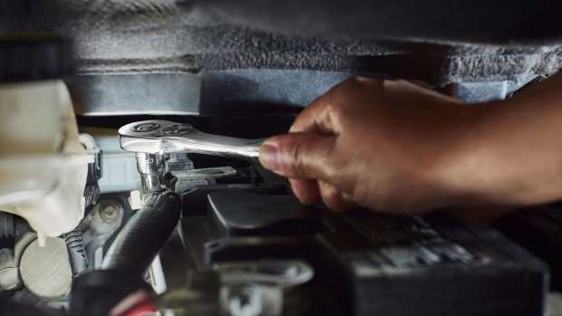 Person repairs a vehicle with a low-profile ratchet.