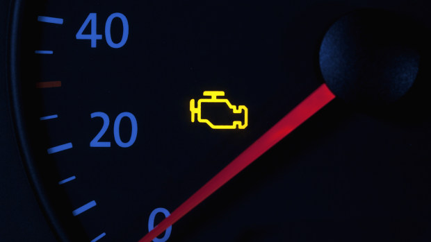 Yellow engine check engine icon on car dashboard.