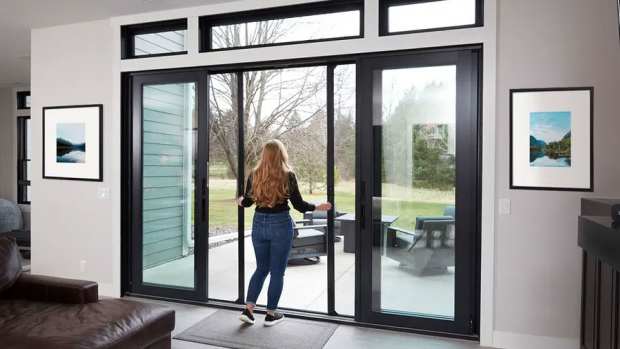 Woman opens screens on large patio doors.
