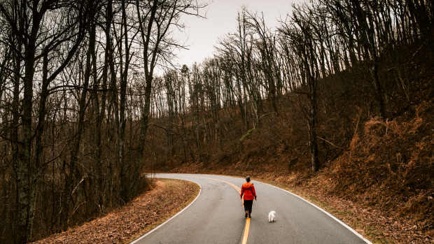 Mature Woman walking the dog on a remote country road in Shenandoah National Park