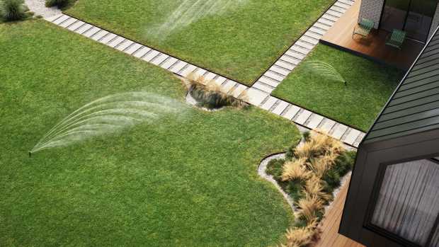 An overhead view of a yard with irrigation systems watering the lawn.