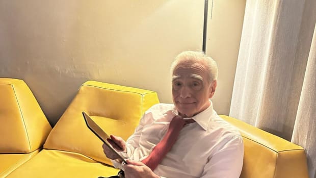 Martin Scorsese on his iPad on a yellow couch scrolling through Letterboxd