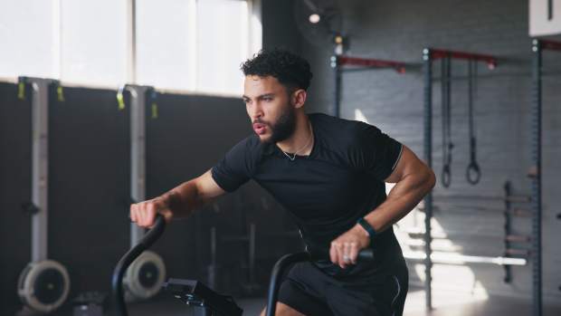Man and bicycle machine in gym for exercise.