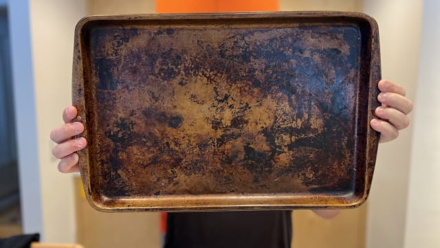 A rimmed baking sheet covered in baked-on grime and grease.