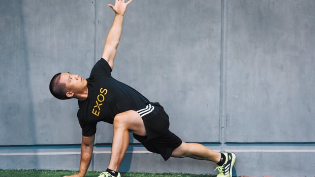 Asian man wearing EXOS T-shirt doing world's greatest stretch