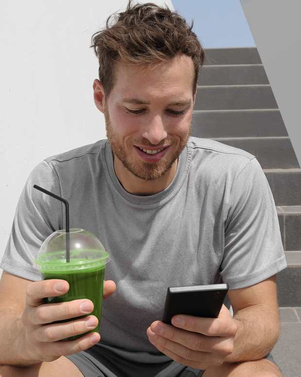 Man sitting on stairs in a grey shirt holding a phone and green smoothie split with three phones with screenshots from WW, Lose It!, and Future, our top picks for the best weight loss apps.