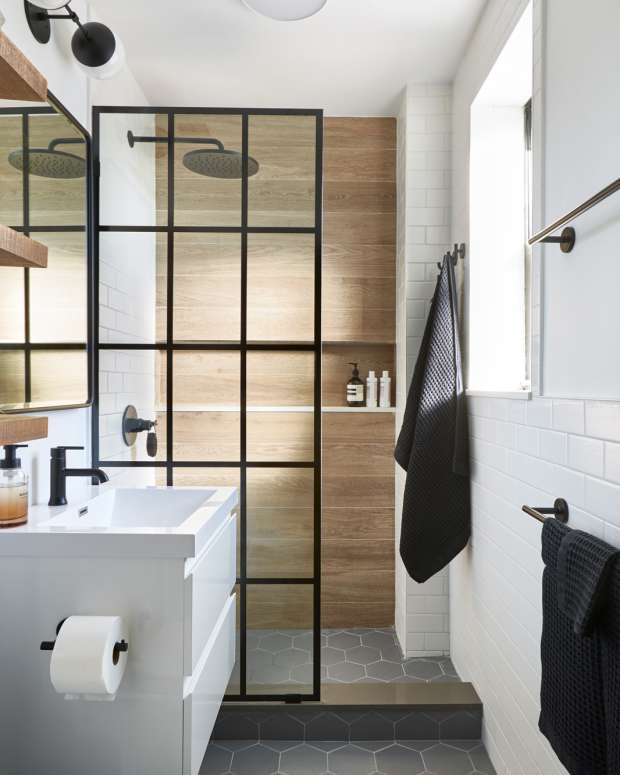 A bathroom with a glass paneled door, hex floor tile, and a wood tiled shower wall.