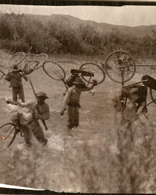 25th Infantry Bicycle Corps carrying bikes across a creek.