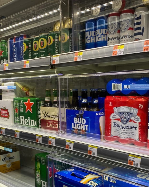 Boxes of beer in a fridge at a grocery store.