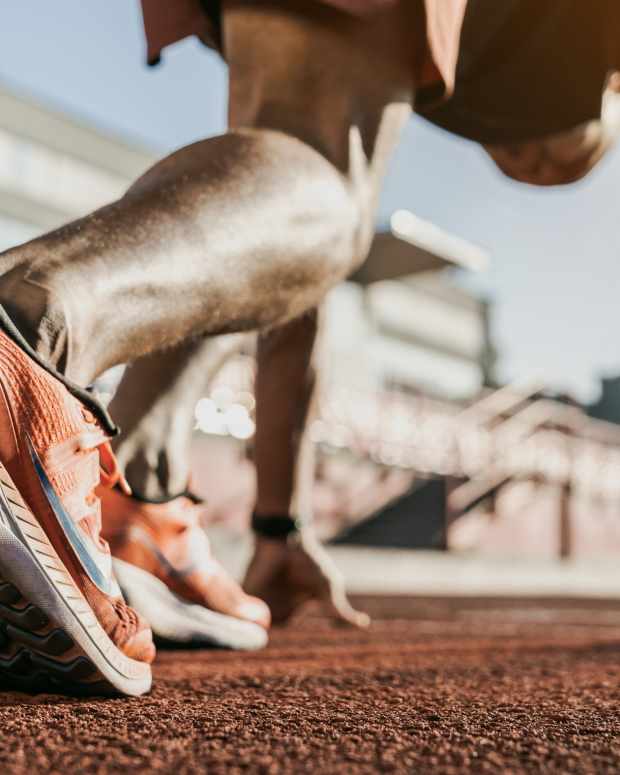 Close up of male athlete getting ready to start running on track.
