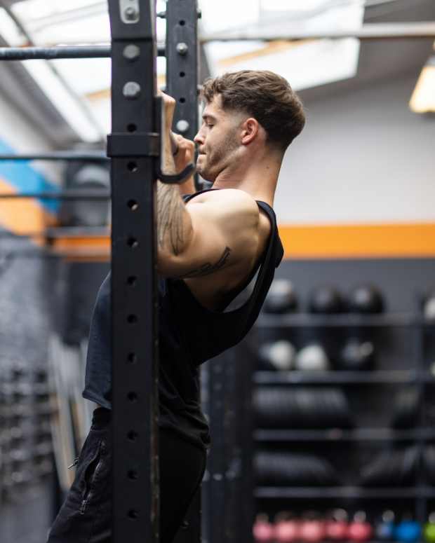 Side view of fit man doing chin-ups on a bar at fitness studio