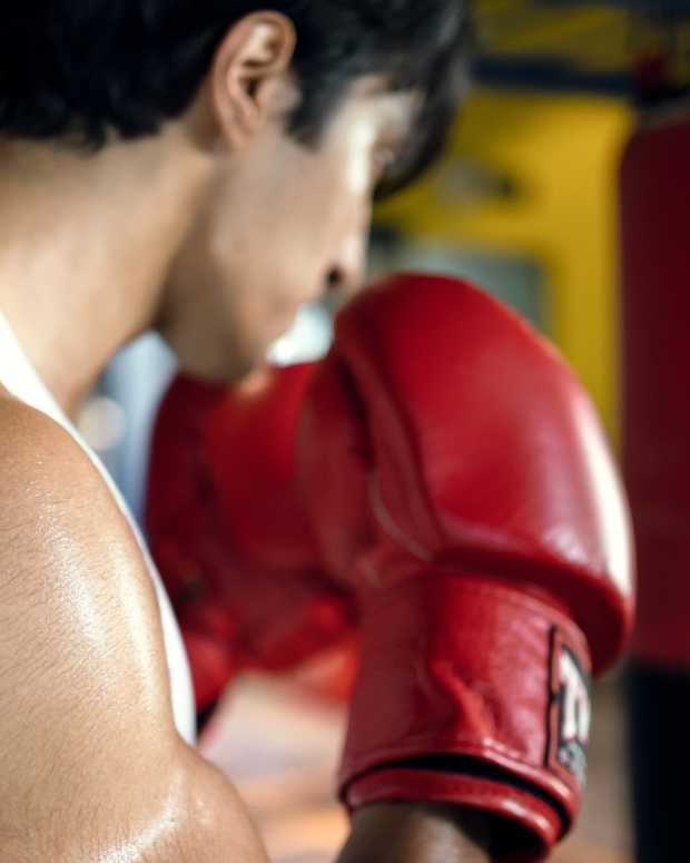 Asian men practice boxing with sandbags in the gym.