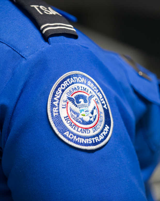 A Transportation Security Administration (TSA) agent's patch is seen as she helps travelers place their bags through the 3-D scanner at the Miami International Airport on May 21, 2019 in Miami, Florida.