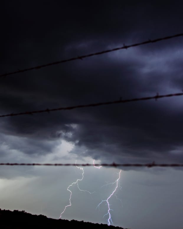 BLACKWELL, OK - MAY 29:  Lighting strikes through a fence and across a field as Tempest Tours storm chase tour guests watch a storm over the Great Plains in the United States of America May 29, 2006 outside of Blackwell, Oklahoma, USA. (Photo by Jeff Hutchens/Getty Images)