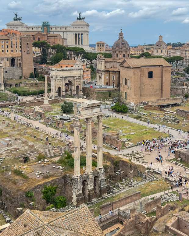 A sweeping aerial view of the Roman Forum in Rome, Italy, showcasing the heart of ancient Rome. The foreground is filled with the ruins of temples, columns, and historic structures, including the prominent Temple of Saturn with its remaining columns standing tall. The Arch of Septimius Severus and other significant monuments are visible among the ruins, with pathways winding through the site where tourists explore. Beyond the Forum, the grand Altare della Patria dominates the skyline, along with the domes of churches and the Palazzo Senatorio on Capitoline Hill. The photo captures the blend of ancient history and modern city life, all under an overcast sky that softens the light and highlights the architectural beauty of Rome's historic center.

Rome, Roma Province, Italy - June 11, 2024