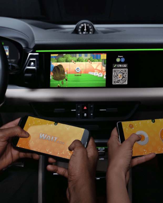 Two people playing Porshe's in-car gaming console