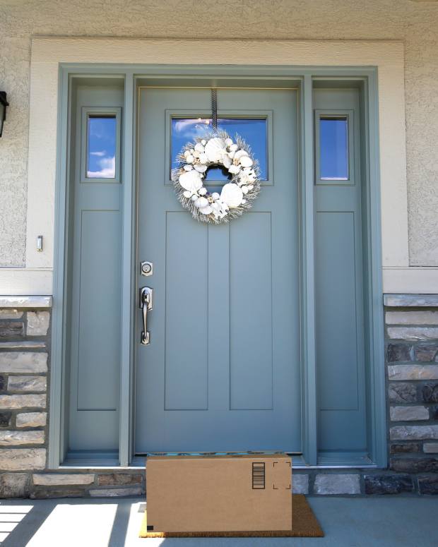 A package sitting on the porch in front of a door—delivery lockboxes can stop porch pirates from stealing it.