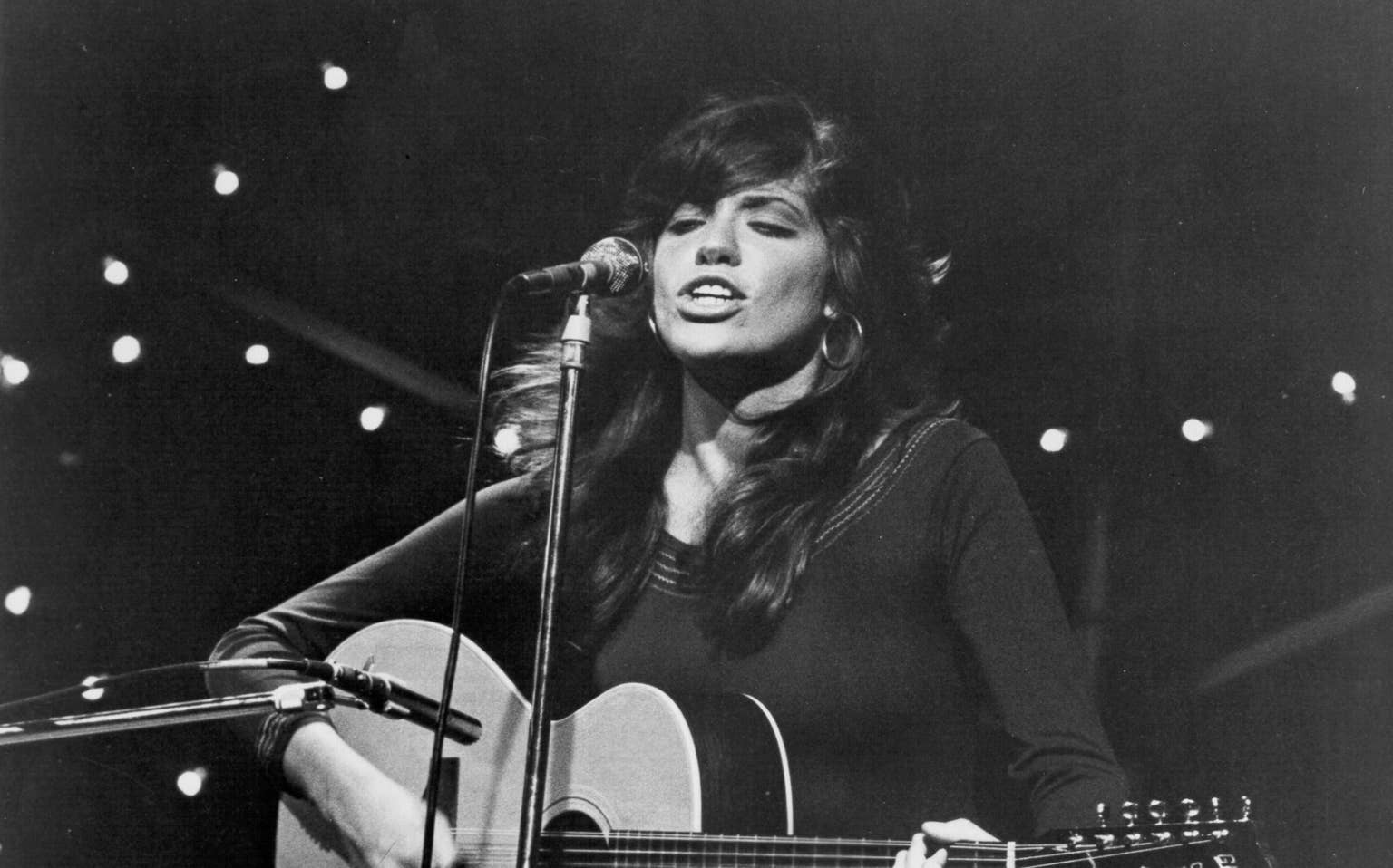 Carly Simon performing with her acoustic guitar during the 1972 breakthrough period.