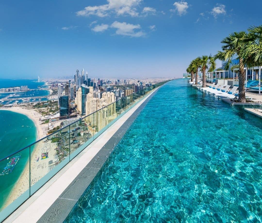The rooftop pool at the Address Beach Resort with a beach and skyline in the background. hotel pools