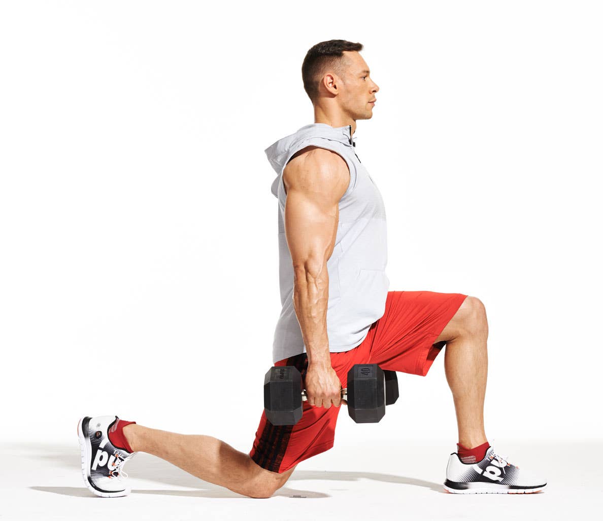 Bodyweight Leg Exercises: Caucasian man in gray tank and red shorts performs dumbbell split squat.