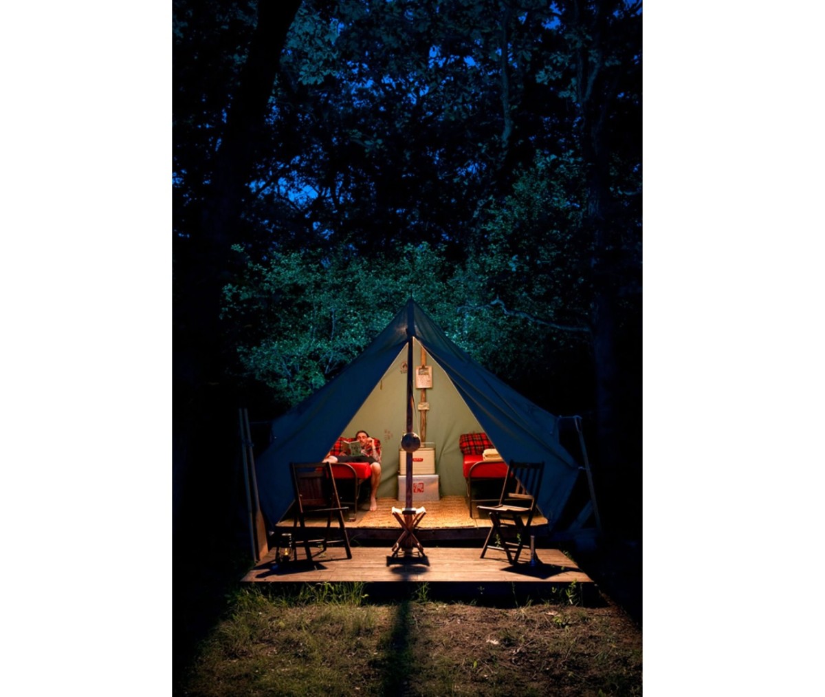 Camp Wandawega tent at night with man inside on bed