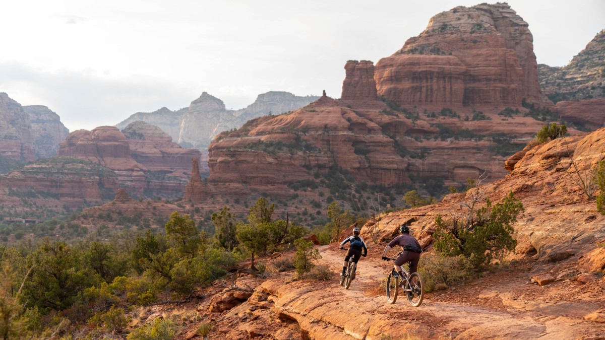Two bikers riding on a red rock trail in Sedona, AZ.