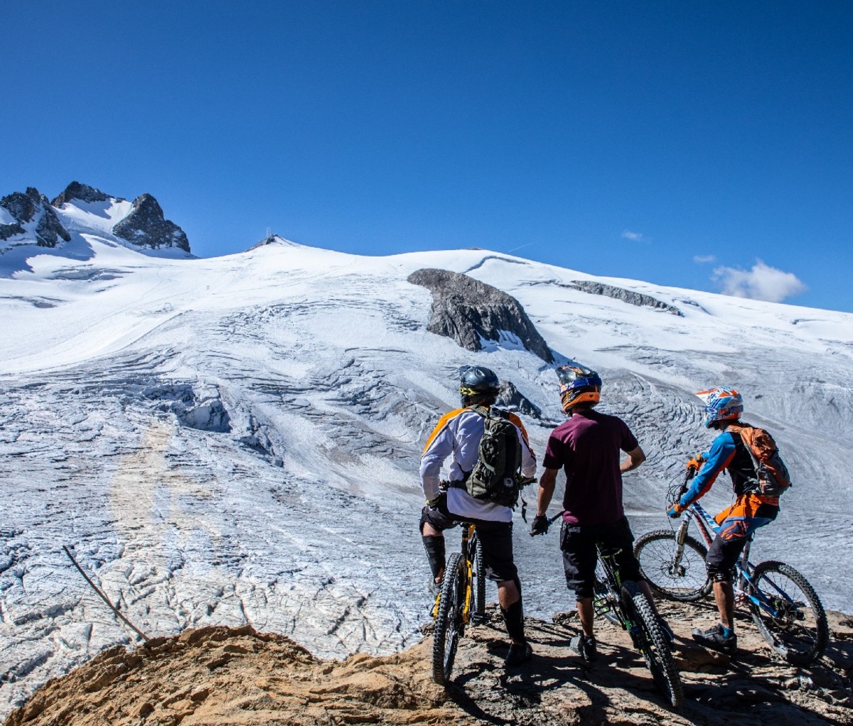 Three mountain bikers on a snowy summit in La Grave, France.