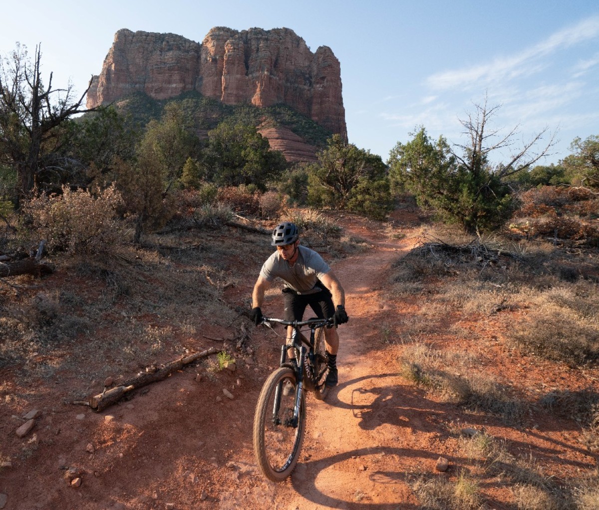 Mountain biker riding down a red rock trail in Sedona, AZ.