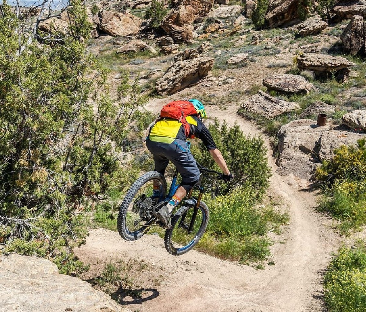 Mountain biker in mid-air on a jump down a bike trail near Grand Junction, CO.