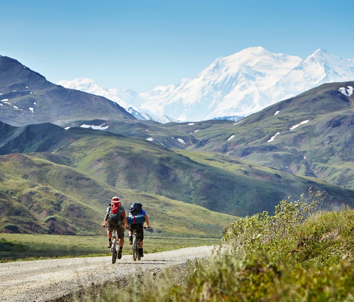 Couple biking on a gravel road in Alaska, near Denali National Park.