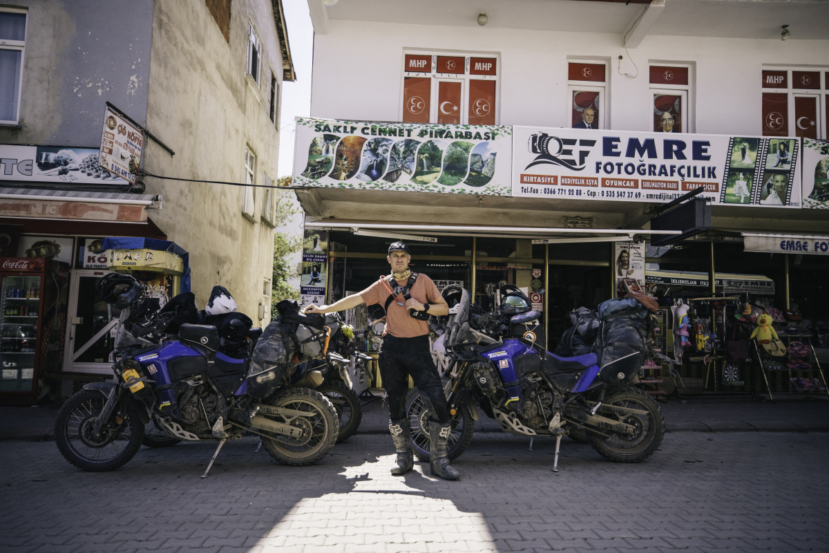 Man standing in front of four motobikes at start of Silk Road moto tour