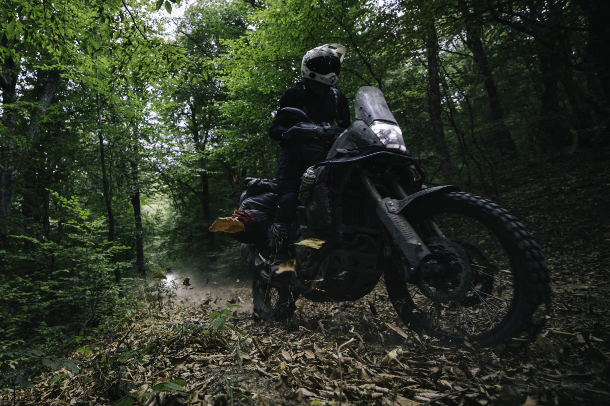 Riding motobike on leafy wooded path in woods along Silk Road
