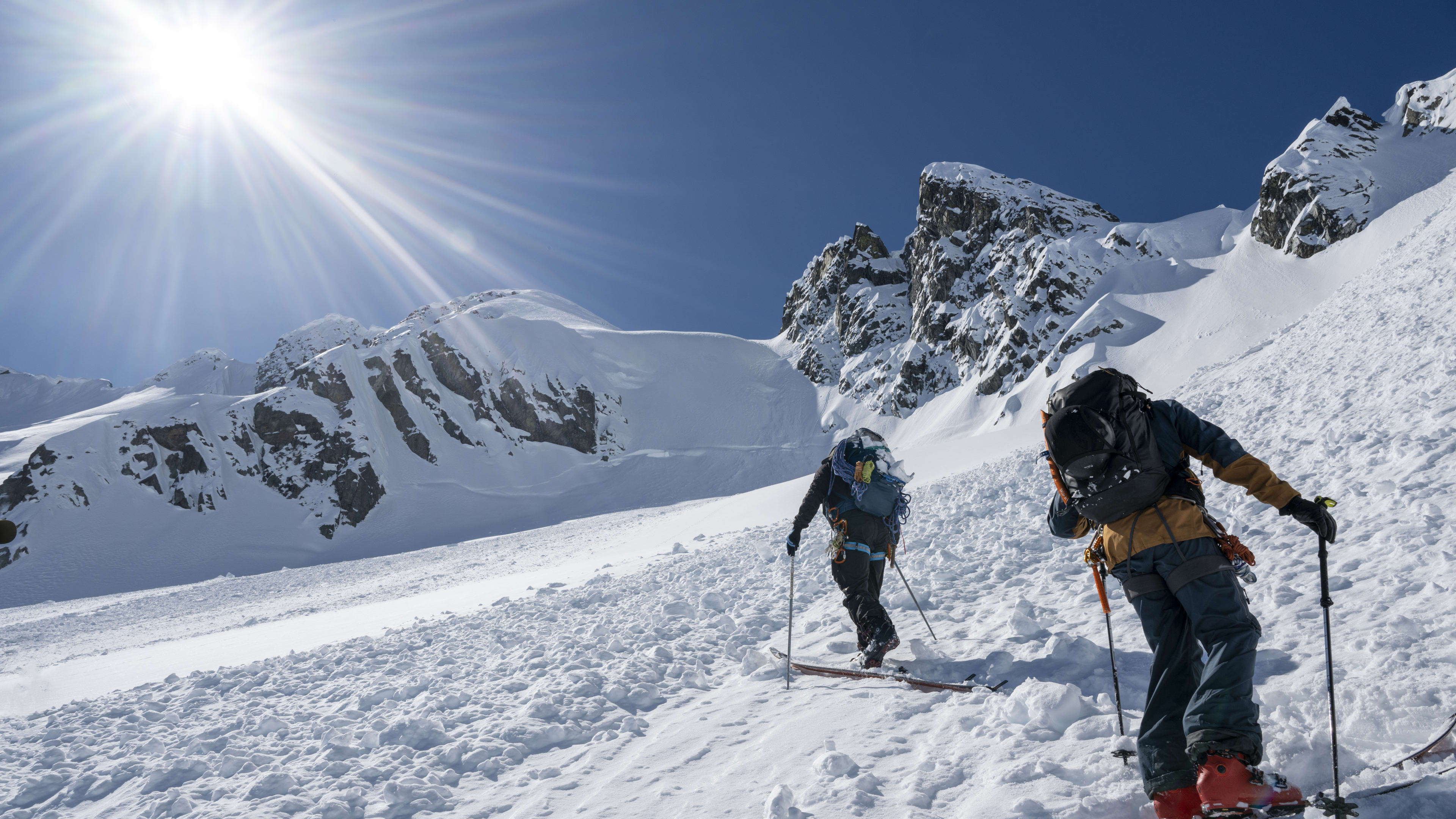 Backcountry skiers cross avalanche slope on mountain, Tantalus Ranges 