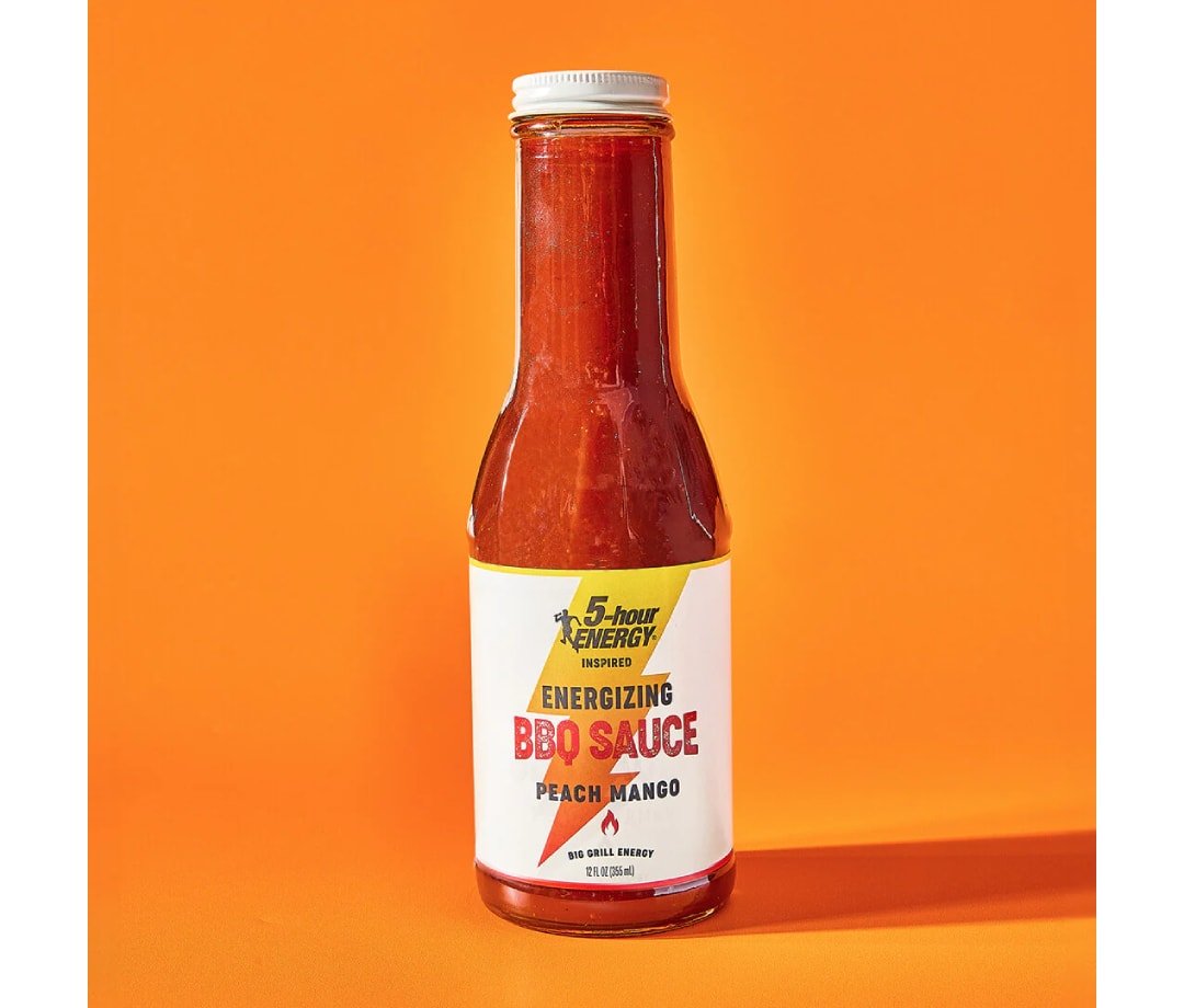 Glass bottle of 5 hour energy barbecue sauce on an orange background, part of Men's Journal's guide to grilling the ultimate chicken thighs.
