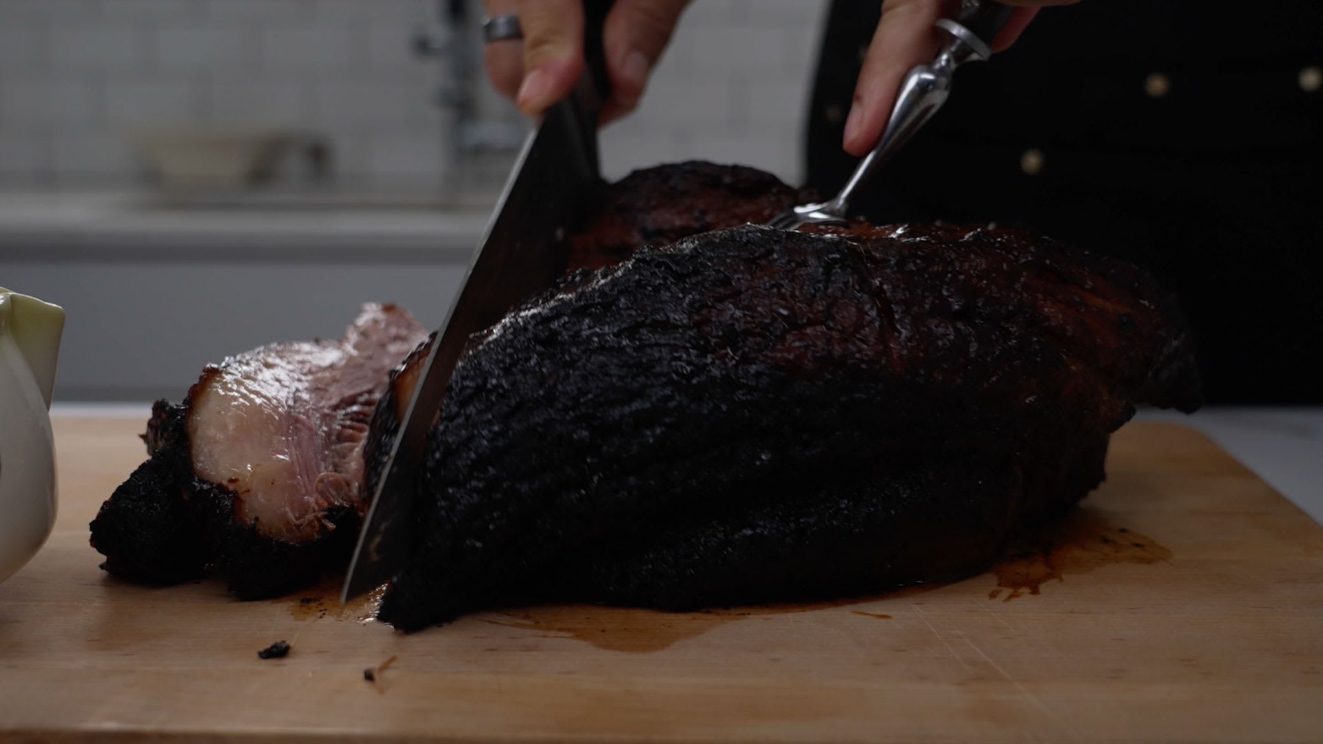 Knife cutting into brisket on cutting board