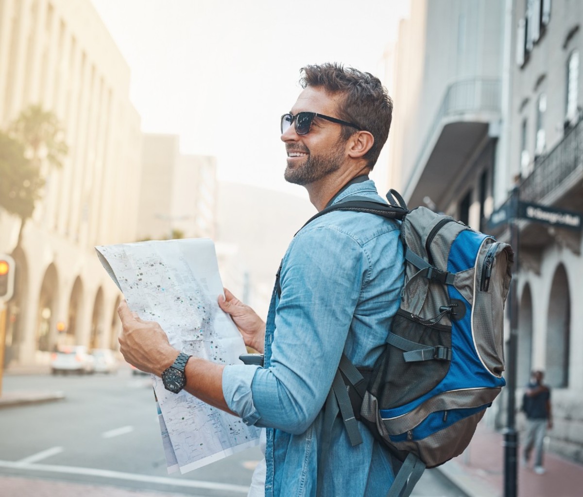 Man in blue shirt and backpack looking at map