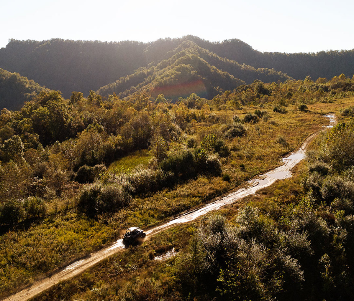 Aerial shot of ATV vehicle driving through wooded trails