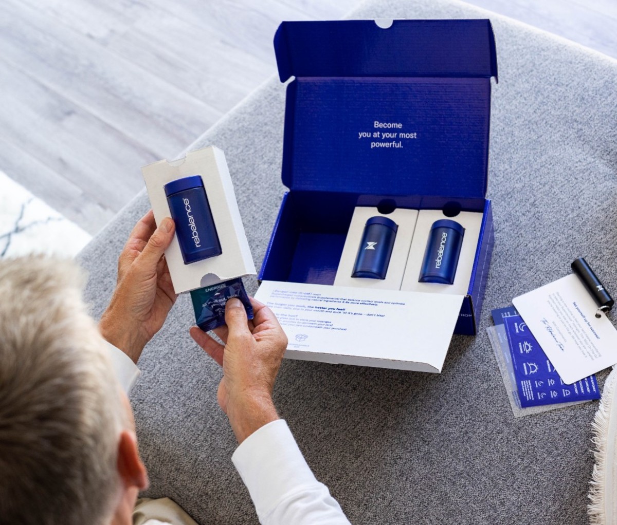 Man opening box of blue supplement bottles