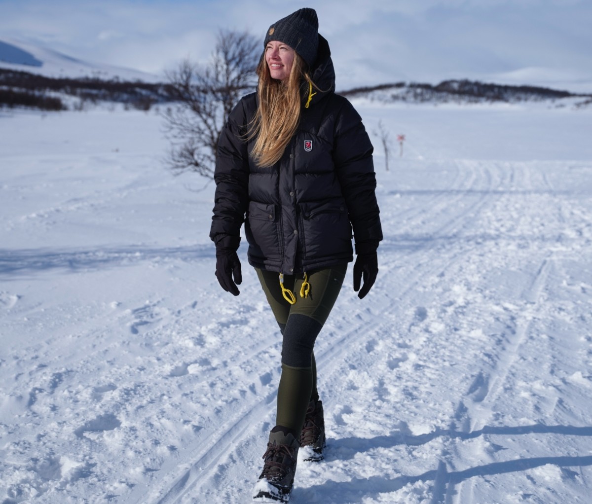 Woman wearing a black Expedition Down Lite jacket walking on a snowy road