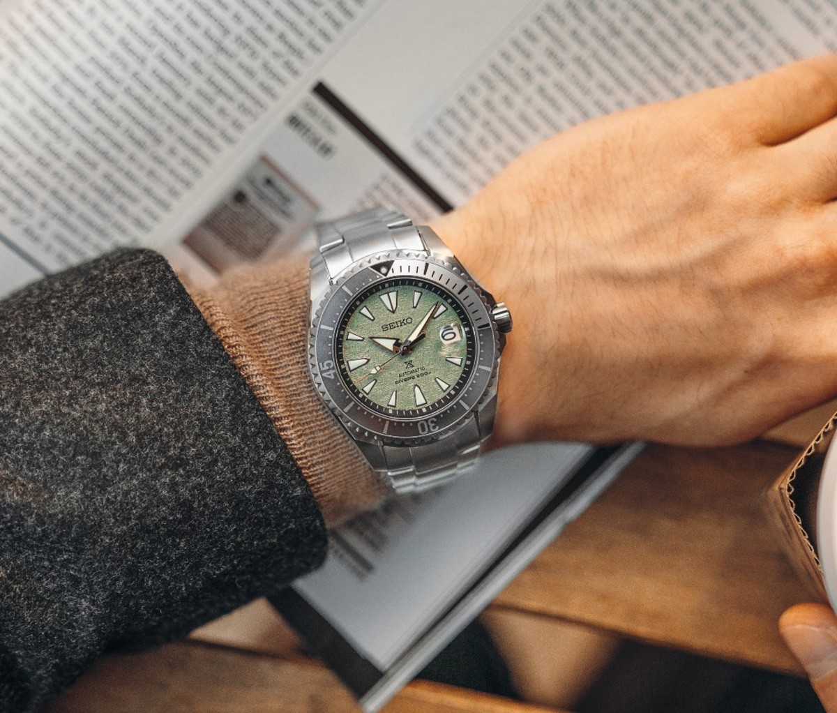 Close-up overhead shot of caucasian man's wrist with silver watch with green face