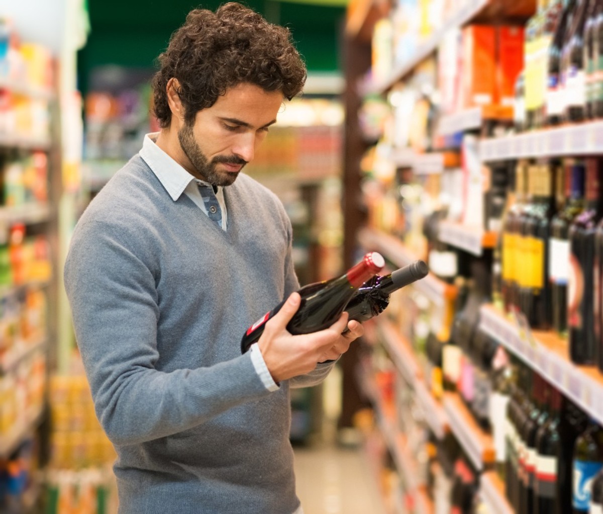 Man choosing between two bottles of wine.