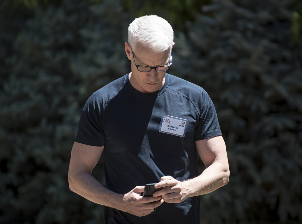 Anderson Cooper, anchor for CNN, checks his mobile phone while walking