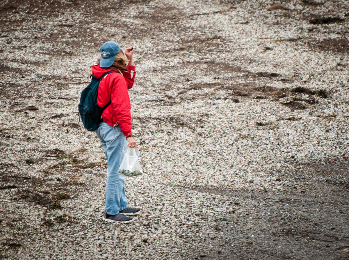 Stop by the beach any day and you will see people placing glass in plastic bags and canisters. This woman inspects a glass piece for her collection. Photo by Travis Burke Stop by the beach any day and you will see people placing glass in plastic bags and canisters. This woman inspects a glass piece for her collection. Photo by Travis Burke