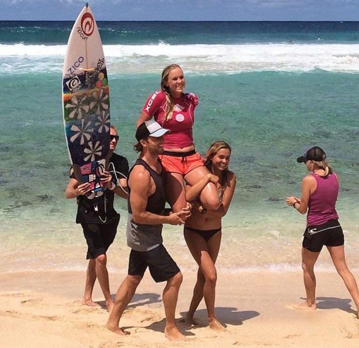 Bethany Hamilton is carried up the beach by her husband Adam and friend after winning the Surf-n-Sea Pipe Pro; photo courtesy Bethany's Facebook page.